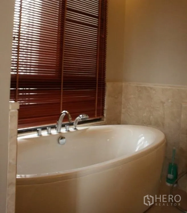 公寓 出租或出售在Watthana, Bangkok - 浴室配椭圆浸泡浴缸，木百叶窗与米色石材墙面。