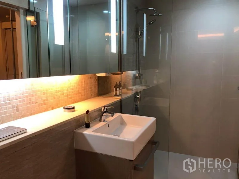 Condominium for rent in Watthana, Bangkok - Contemporary bathroom featuring vanity sink, illuminated mirror and glass shower.