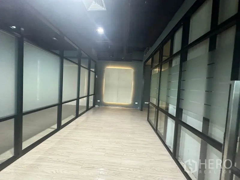 Office Space for rent in Bang Rak, Bangkok - Interior hallway bordered by frosted glass offices under a dark industrial ceiling.