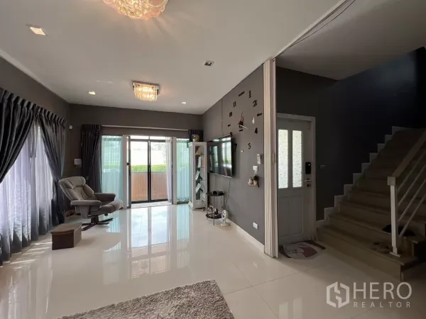 บ้าน ให้เช่าหรือขายในLat Krabang, Bangkok - ห้องนั่งเล่นมองไปยังประตูกระจกบานเลื่อนและบันไดราวสีขาว