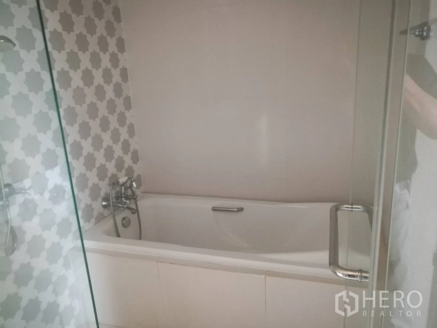 公寓 出售在Khlong Toei, Bangkok - 现代浴室，白色浴缸、灰色图案瓷砖与玻璃隔断。