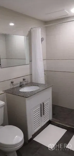 คอนโด ให้เช่าในKhlong Toei, Bangkok - ห้องน้ำโทนสว่างพร้อมเคาน์เตอร์ลายหินอ่อน อ่างล้างหน้า กระจก และพื้นที่อาบน้ำผ้าม่าน