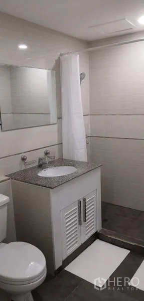 คอนโด ให้เช่าในKhlong Toei, Bangkok - ห้องน้ำโทนสว่างพร้อมเคาน์เตอร์ลายหินอ่อน อ่างล้างหน้า กระจก และพื้นที่อาบน้ำผ้าม่าน