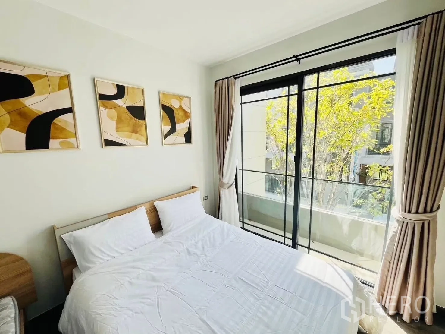 ทาวน์เฮาส์ for rent in Suan Luang, Bangkok - ห้องนอนสว่างพร้อมเตียงและภาพติดผนัง ประตูกระจกเปิดออกสู่ระเบียงมีต้นไม้