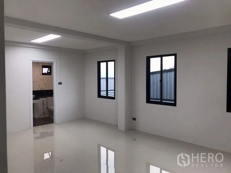 Warehouse for rent or sale in Nong Chok, Bangkok - Bright office room in the warehouse with glossy tile floor, two black-frame windows and a door to the restroom.