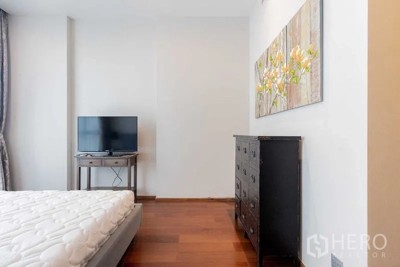 Condominium for rent - Bedroom corner with TV on a stand and a dark chest of drawers.