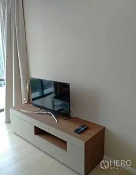 公寓 出租在Watthana, Bangkok - 木质电视柜与平面电视，浅色窗帘和浅色木地板。