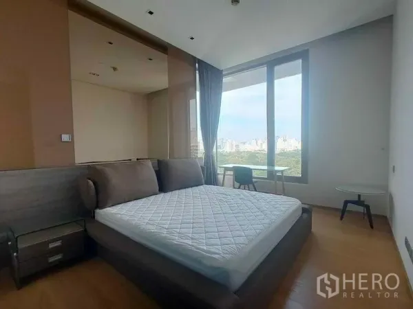 公寓 出租在Bang Rak, Bangkok - 采光充足的卧室，落地窗、双人床与床头柜，可眺望绿意与曼谷天际线。