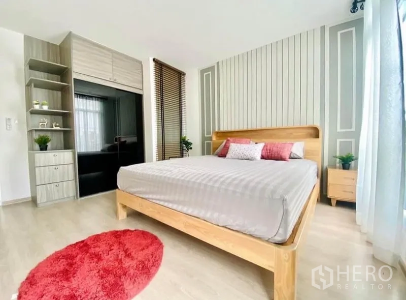 联排别墅 出租在Prawet, Bangkok - 主卧带嵌入式衣柜、落地窗与特色背景墙。