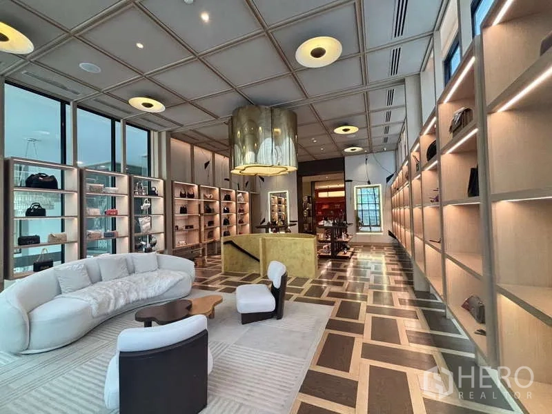 Retail Space for rent in Khlong Toei, Bangkok - Luxury showroom lounge with illuminated built-in shelves, statement chandelier and seating area.