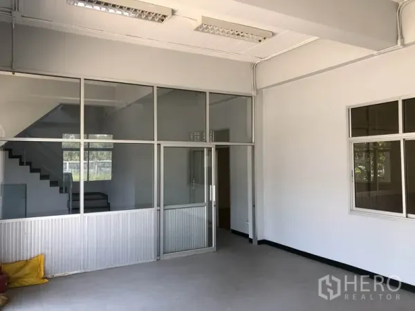 Factory for rent in Lat Lum Kaeo, Pathum Thani - Ground-floor office area with glass partitions and a staircase behind
