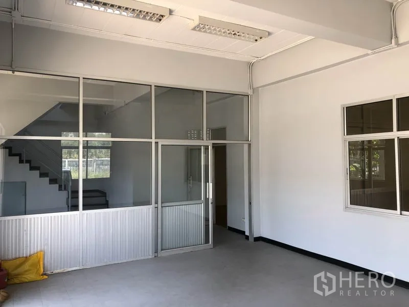 Factory for rent in Lat Lum Kaeo, Pathum Thani - Ground-floor office area with glass partitions and a staircase behind