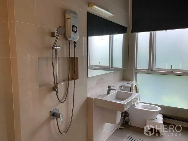 联排别墅 出租在Khan Na Yao, Bangkok - 浅色浴室，电热水器、淋浴、洗手台与磨砂窗。