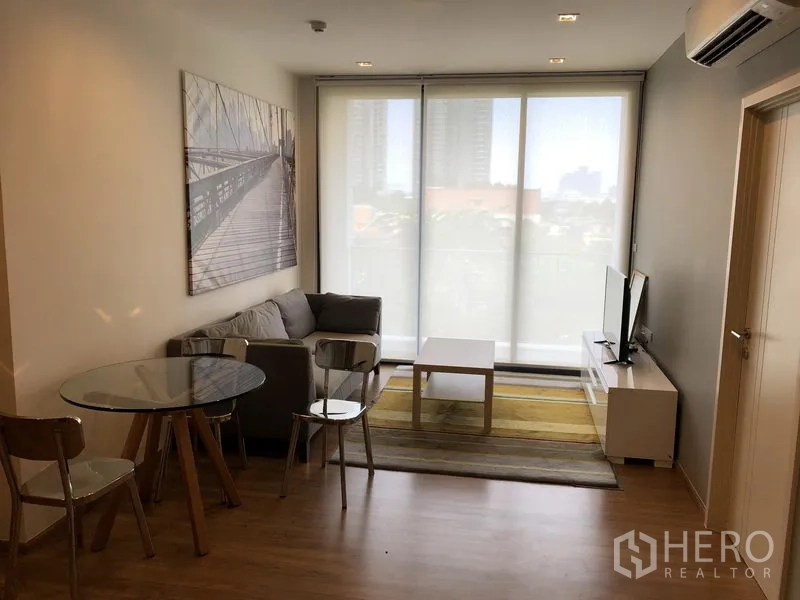 公寓 出租在Watthana, Bangkok - 开放式起居区，卷帘、沙发、餐桌与电视柜面向阳台。