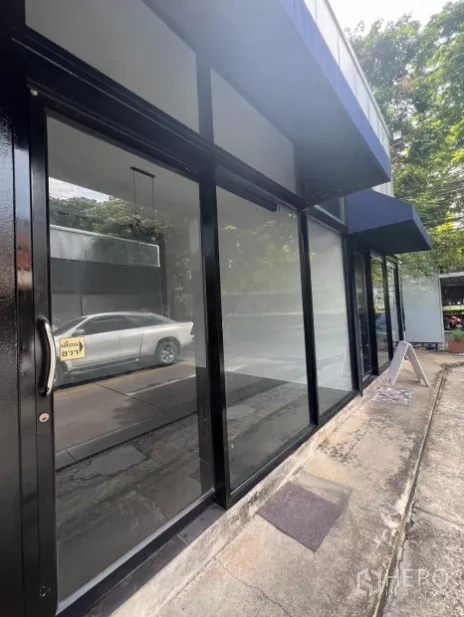 Retail Space for rent in Khlong Toei, Bangkok - Side view of the shop showing floor-to-ceiling glass facade and walkway under a blue canopy.