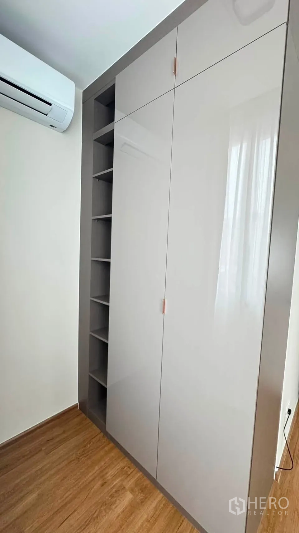 Townhouse for rent in Bang Phli, Samut Prakan - Built-in glossy wardrobe with open shelving beside an air-conditioning unit.