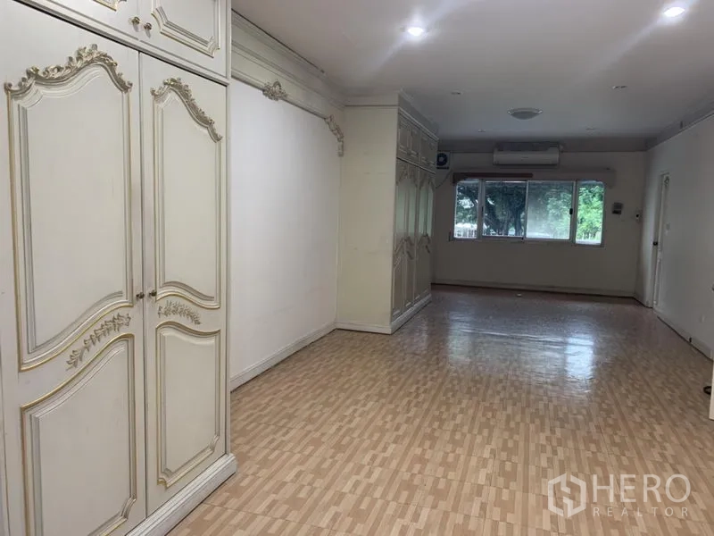 Townhouse for rent in Wang Thonglang, Bangkok - Large bedroom with wood-look floor, classic built-in wardrobes and wide window.