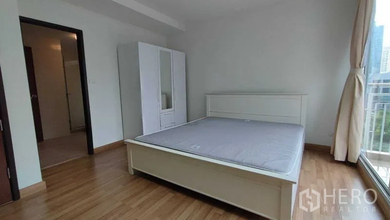 คอนโด ให้เช่าในKhlong Toei, Bangkok - ห้องนอนสว่าง เตียงและตู้เสื้อผ้าสีขาว หน้าต่างบานใหญ่เห็นเส้นขอบฟ้าเมือง