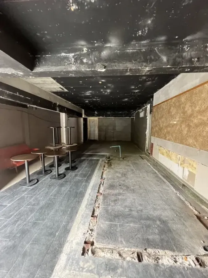 零售空间 出租在Watthana, Bangkok - 狭长开间商铺，黑色裸顶，地面有管线沟槽并摆放少量圆桌。