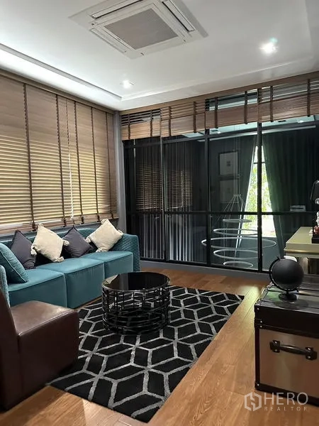 บ้าน ให้เช่าในPhra Khanong, Bangkok - มุมนั่งเล่นครอบครัว โซฟาสีน้ำเงิน พรมลาย และผนังกระจก