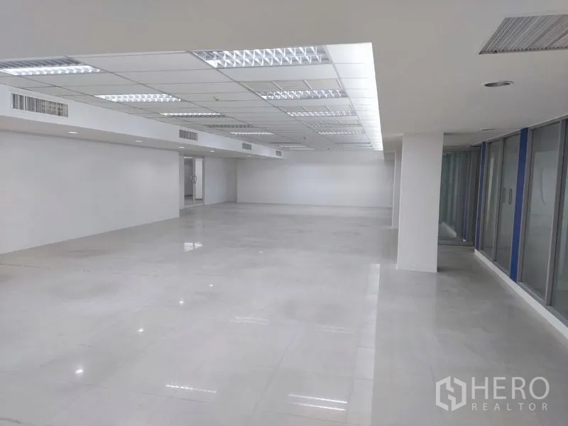 Office Space for rent in Chatuchak, Bangkok - Light-filled open-plan office with suspended ceiling lights and windows along the side.