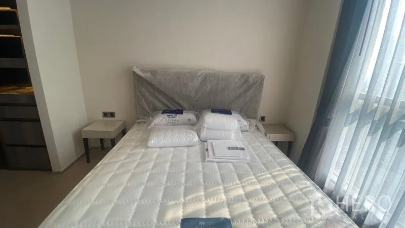 Condominium for rent - Sunlit bedroom with queen mattress, twin side tables and large window with sheer curtains.