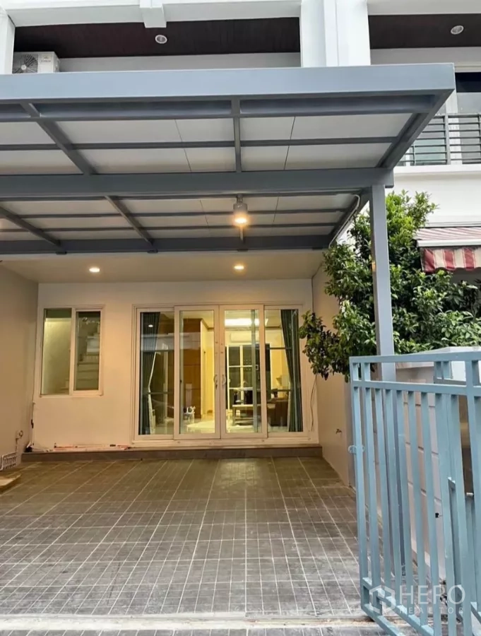 Townhouse for rent in Wang Thonglang, Bangkok - Townhouse facade with gated entrance and covered two-car carport at dusk lighting