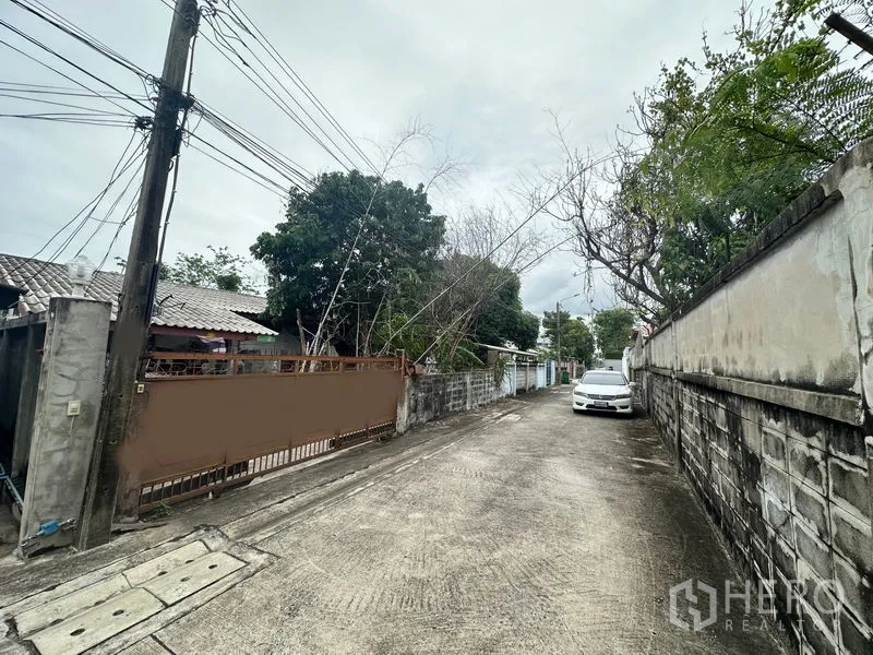ที่ดิน ขายในPhra Khanong, Bangkok - มุมมองตามซอย เห็นประตูที่ดิน กำแพงข้างเคียง และรถที่จอดอยู่ไกลออกไป