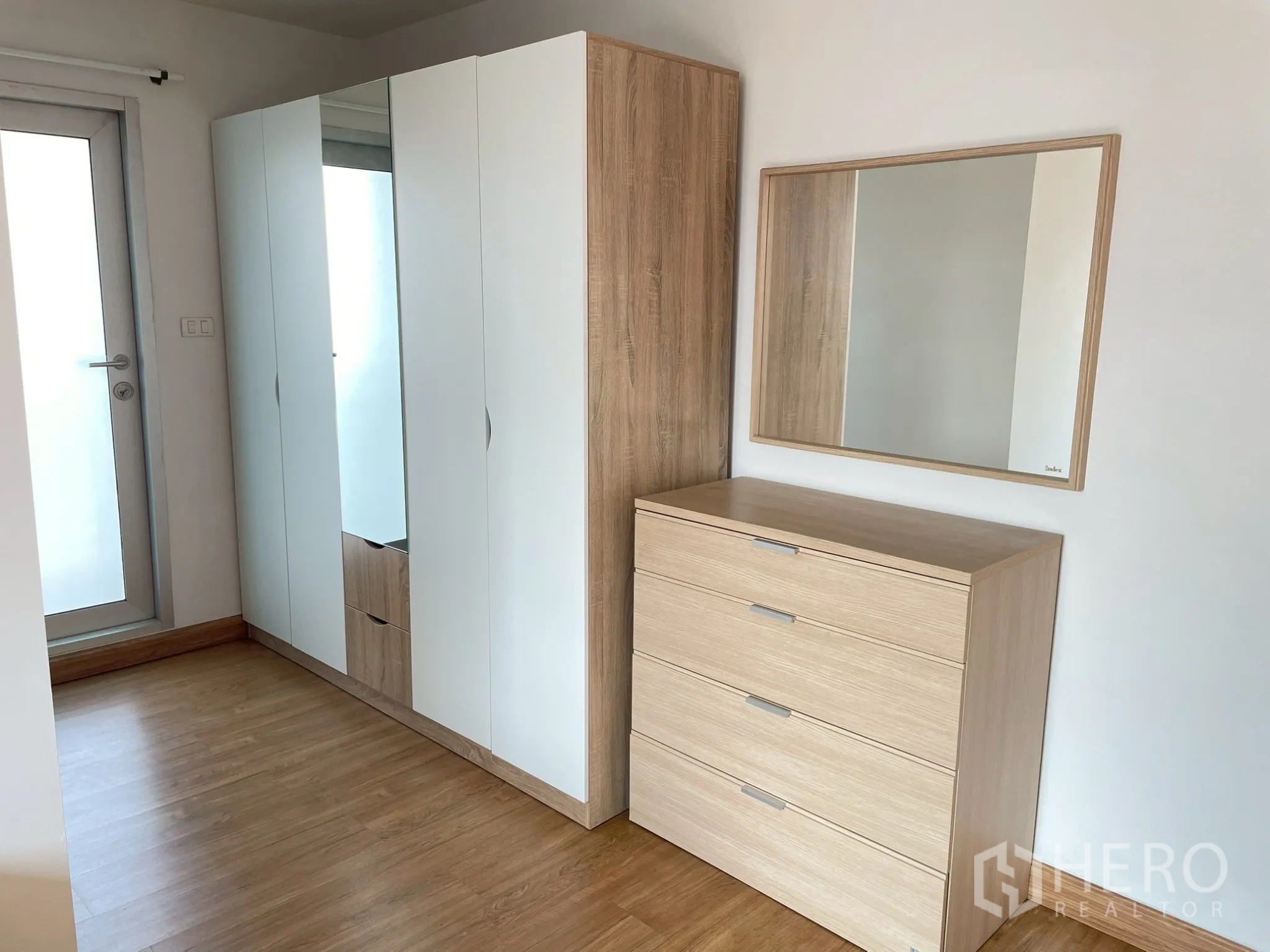 Apartment for rent in Khlong Toei, Bangkok - Bedroom storage with white wardrobe, dresser, and mirror on wood flooring.