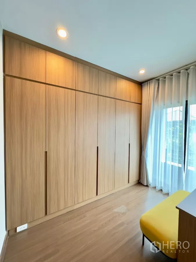 独立式住宅 出租在Samut Prakan - 整面内置衣柜，暖色灯光与木地板。