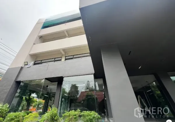 พื้นที่ขายปลีก ให้เช่าในSuan Luang, Bangkok - อาคารค้าปลีกสมัยใหม่ ผนังหินสีเข้ม เสากลาง และกระจกเต็มบาน รายล้อมด้วยต้นไม้