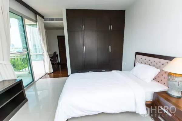 Apartment for rent in Sathon, Bangkok - Bright bedroom with built-in wardrobe and balcony access overlooking greenery and city views.