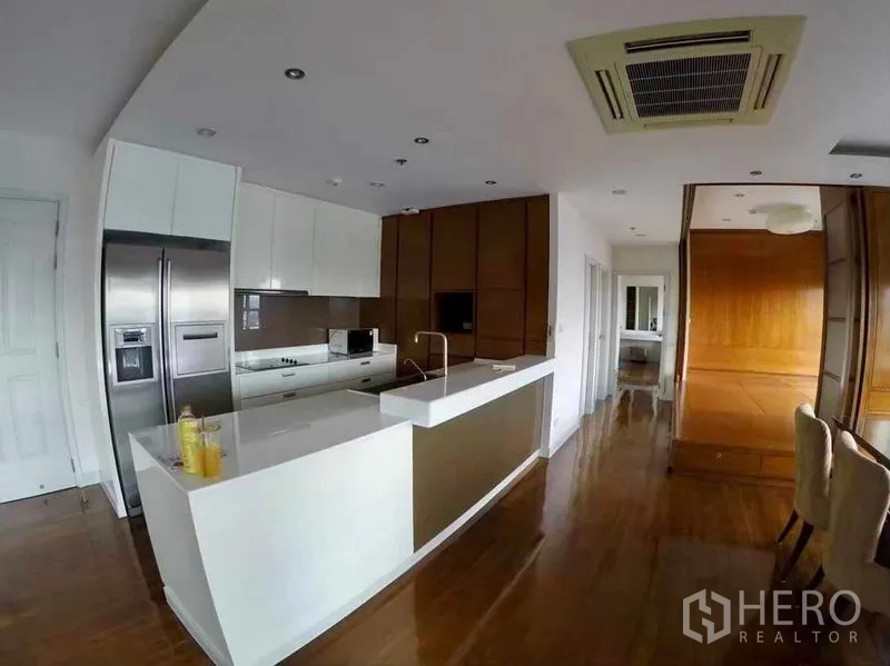 Condominium for rent or sale in Khlong San, Bangkok - Open-plan kitchen with long white peninsula beside the dining area in a Khlong San condo.