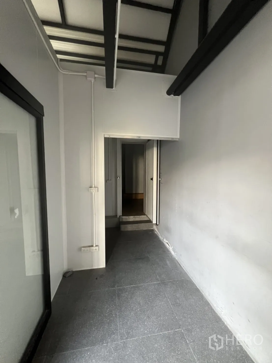 พื้นที่ขายปลีก ให้เช่า - โถงทางเดินด้านหลังเชื่อมสู่ห้องบริการ พร้อมปลั๊กไฟและขั้นบันไดเตี้ย.