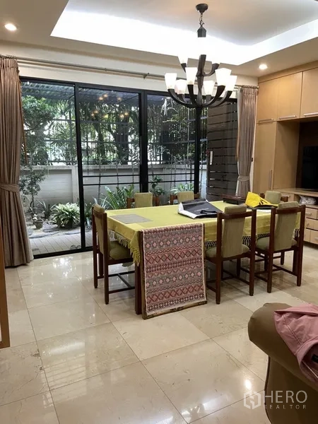 Home Office for rent or sale in Phra Khanong, Bangkok - Dining area with chandelier and sliding glass doors opening to a small garden patio.