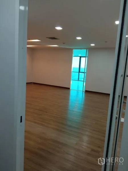 办公空间 出租在Huai Khwang, Bangkok - 空置办公室，木地板、嵌入式照明，玻璃门通向采光区。