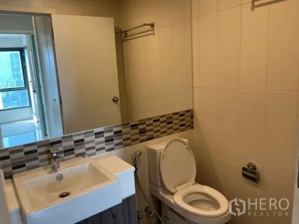 คอนโด ขายในPhaya Thai, Bangkok - ห้องน้ำปูกระเบื้องสว่าง พร้อมอ่างล้างหน้า กระจก และโถสุขภัณฑ์ในคอนโดพญาไท