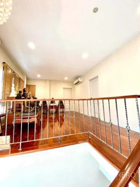 Detached House for sale in Saphan Sung, Bangkok - Upper landing with wooden flooring and railing leading to bright multipurpose family area.