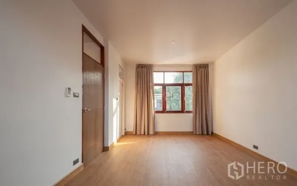 独立式住宅 出售在Chatuchak, Bangkok - 宽敞卧室，木地板、素色墙面与大窗帘。