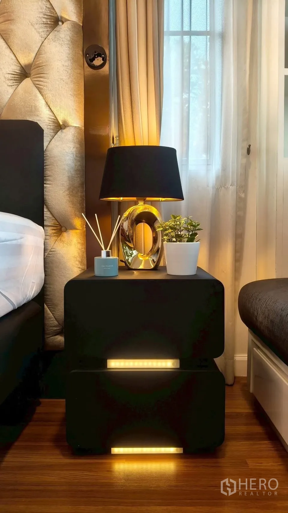 บ้าน ให้เช่าหรือขายในMueang Samut Prakan, Samut Prakan - โต๊ะข้างเตียงพร้อมโคมไฟสมัยใหม่ กระถางต้นไม้ และก้านกระจายกลิ่น ข้างหัวเตียงบุผ้า