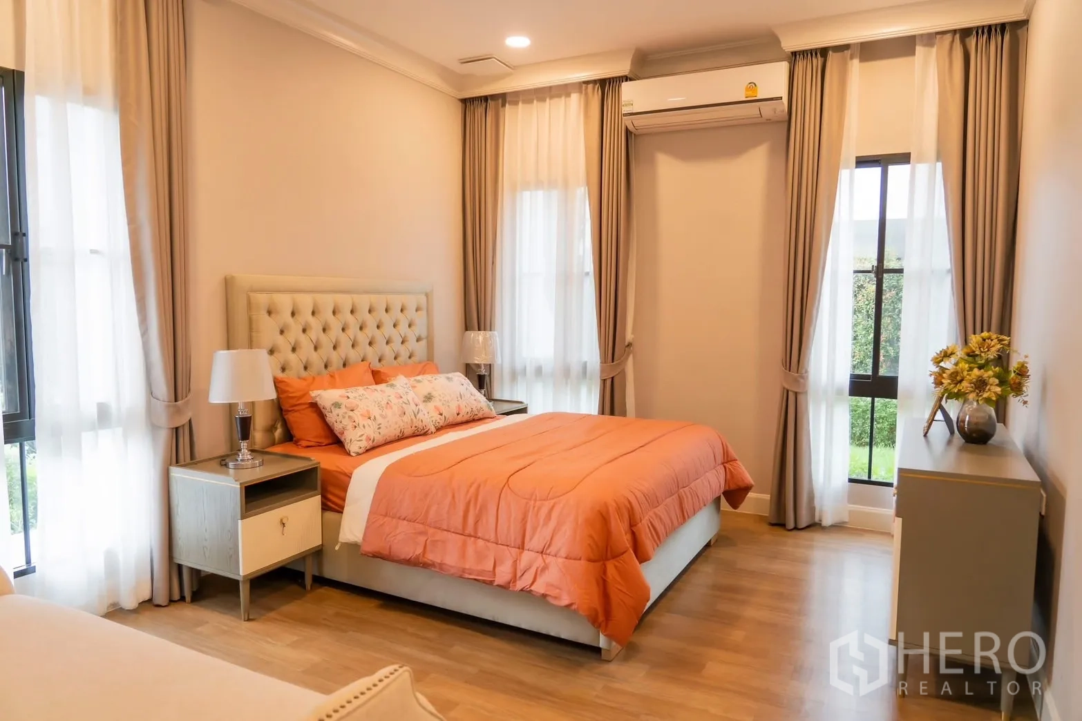 Detached House for rent in Saphan Sung, Bangkok - Ground-floor bedroom with orange duvet and corner windows.