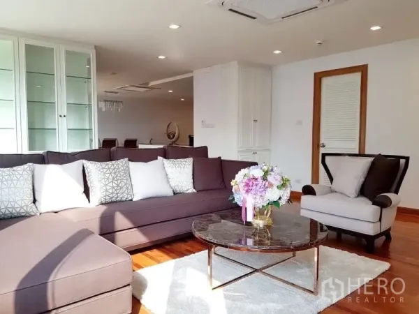 Condominium for rent in Watthana, Bangkok - Spacious living room with an L-shaped sofa, armchair, and round coffee table.