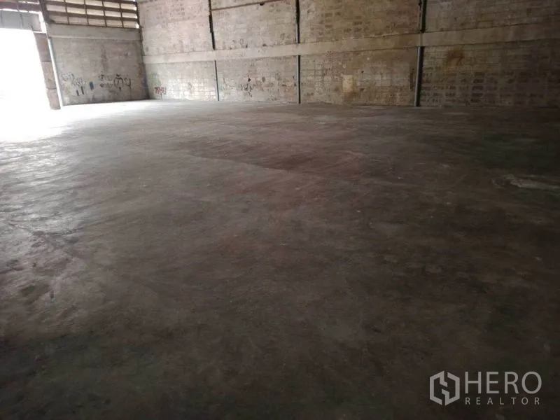 Warehouse for rent in Mueang Samut Sakhon, Samut Sakhon - Spacious warehouse interior with concrete floor, high block walls and light from a large entry.