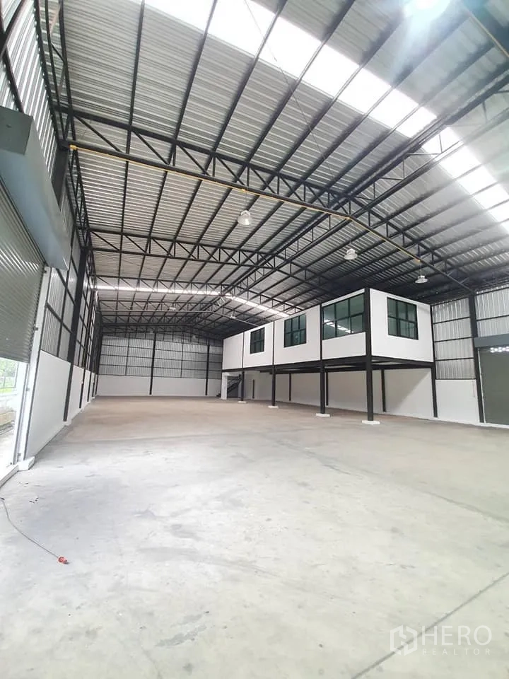 货栈 出租在Bang Khen, Bangkok - 内部侧视，配大型卷闸门、高屋顶与抬高的夹层办公室结构。