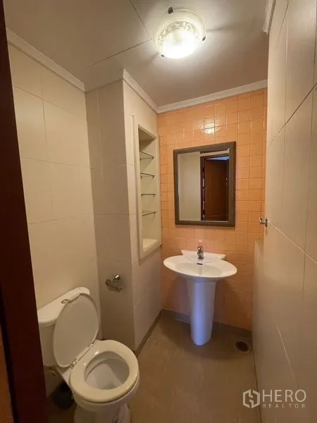 Condominium for rent in Watthana, Bangkok - Guest bathroom with pedestal sink, toilet and wall shelving.