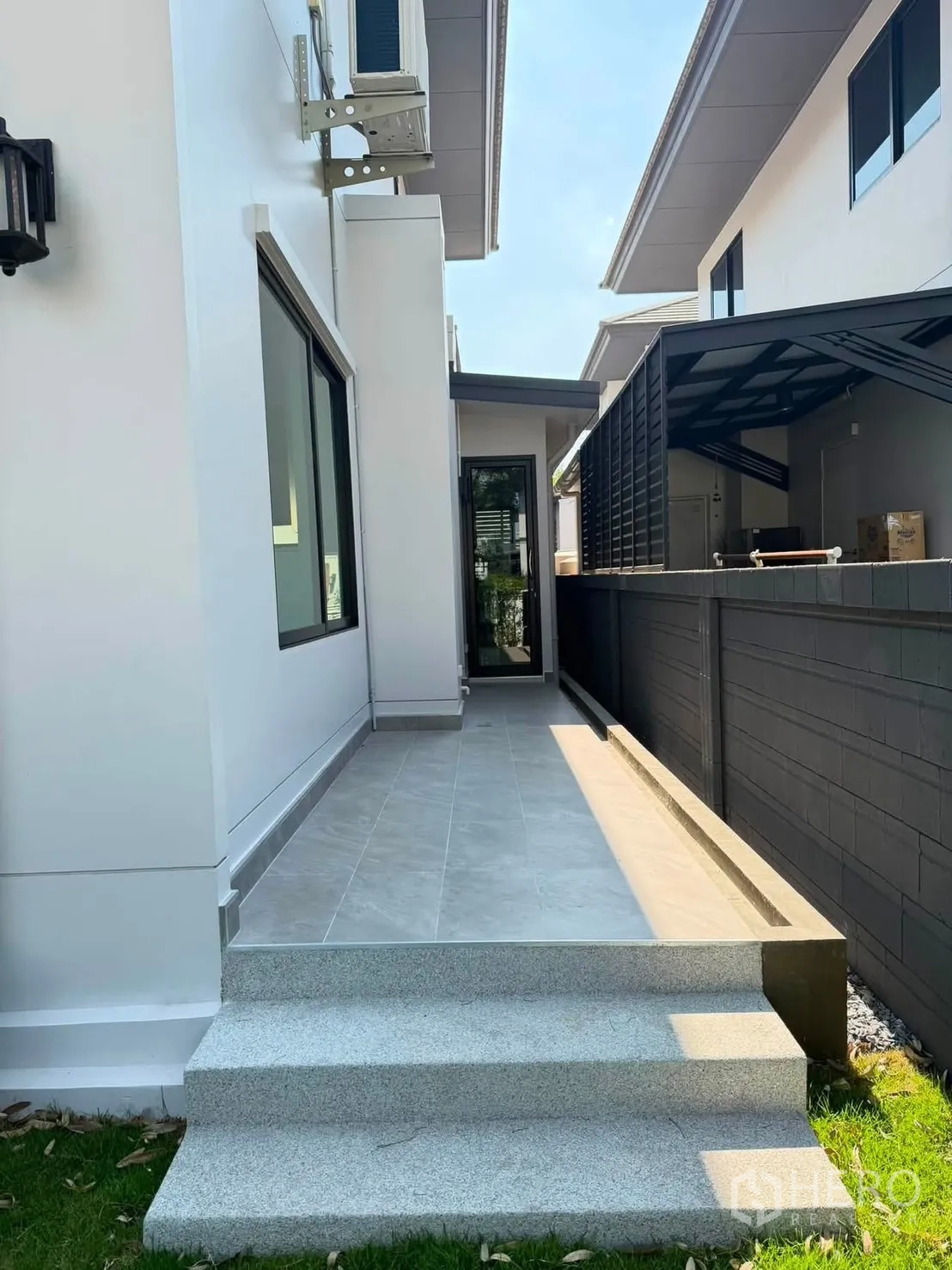 Detached House for rent or sale in Prawet, Bangkok - Side terrace with tiled steps and lawn beside the white house.