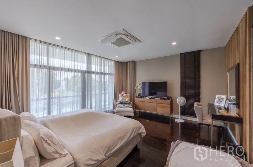 Detached House for rent or sale in Bang Kapi, Bangkok - Master bedroom facing TV and vanity next to large windows.