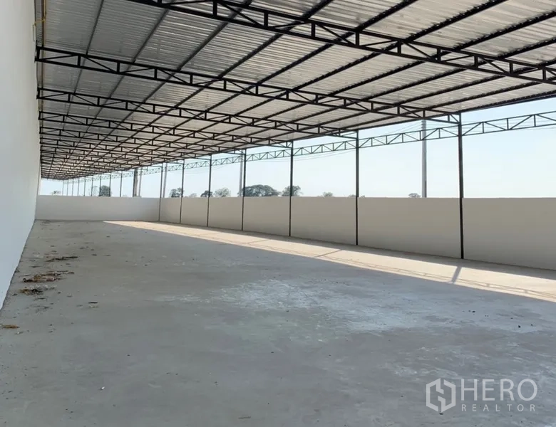 Warehouse for rent in Samut Prakan - Long covered loading bay with open sides and wide concrete apron next to the warehouse.