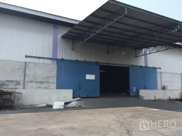 Warehouse for rent in Pathum Thani - Warehouse exterior with large blue sliding doors and a covered loading bay.