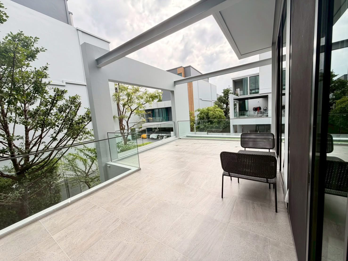 Detached House for rent in Saphan Sung, Bangkok - Expansive sky terrace with glass balustrade, outdoor seating and views of modern neighboring homes.